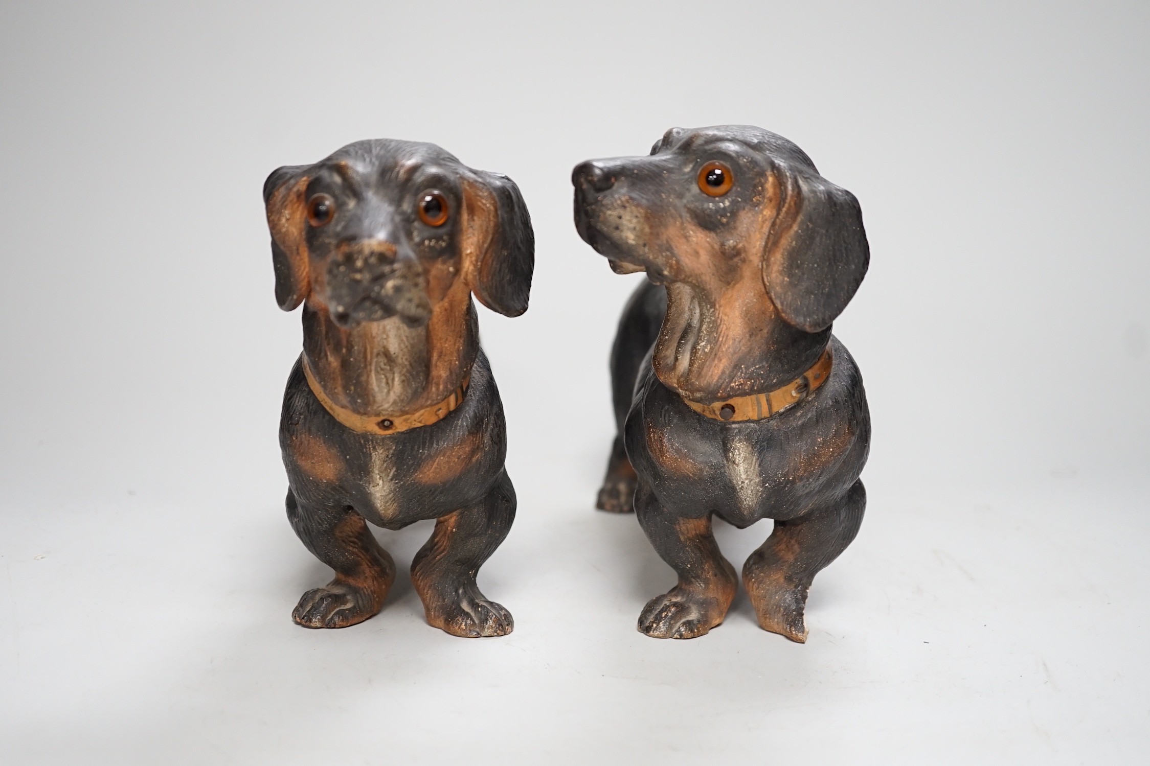 A pair of Austrian cold painted terracotta models of Dachshunds, one paw damaged, inset glass eyes 28cm long